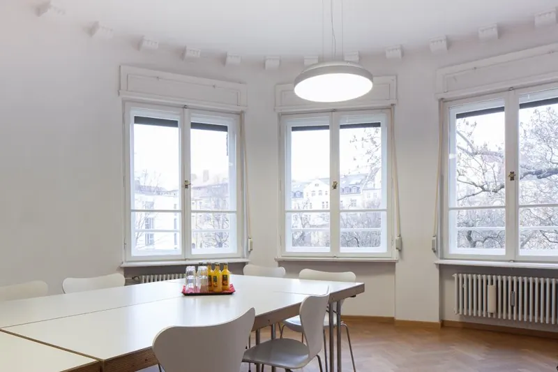 Erkerzimmer in der Seidlvilla mit großen Fenstern im Erker und weißen Tischen