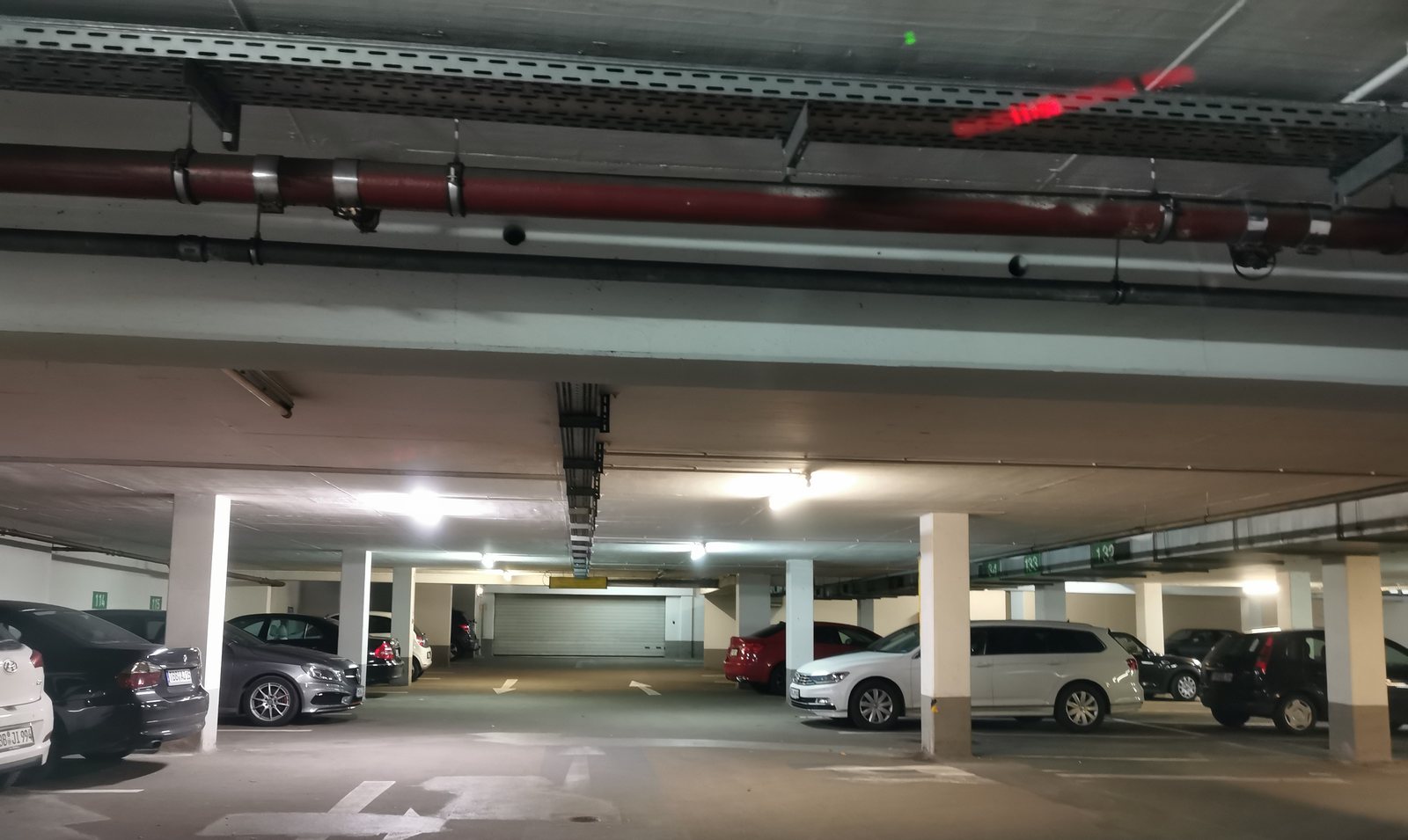 Tiefgarage einer Wohnanlage mit nummerierten Stellplätzen und parkenden Autos