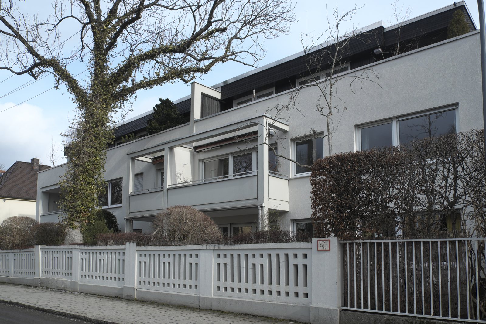 Mehrfamilienhaus mit Balkonen und Gartenzaun in München-Obermenzing