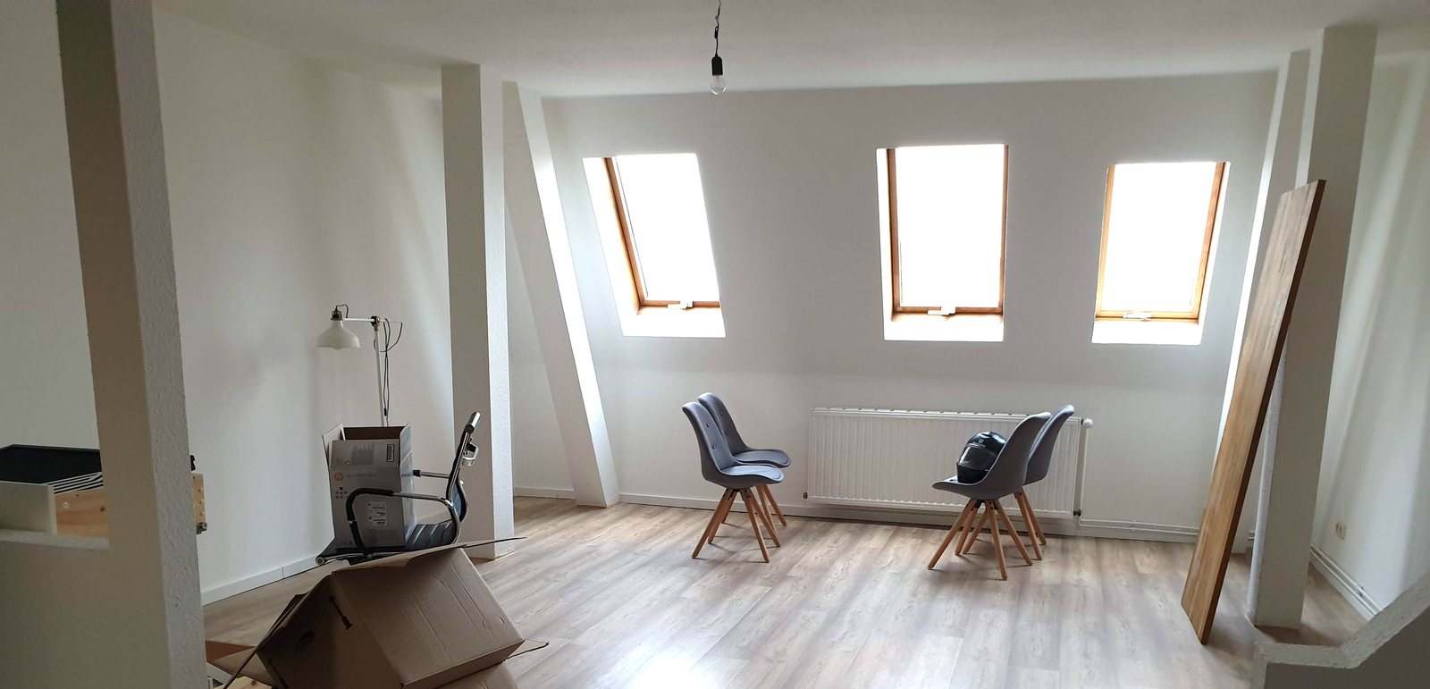 Helle, fast leere Dachgeschosswohnung mit Umzugskarton und Dachfenstern