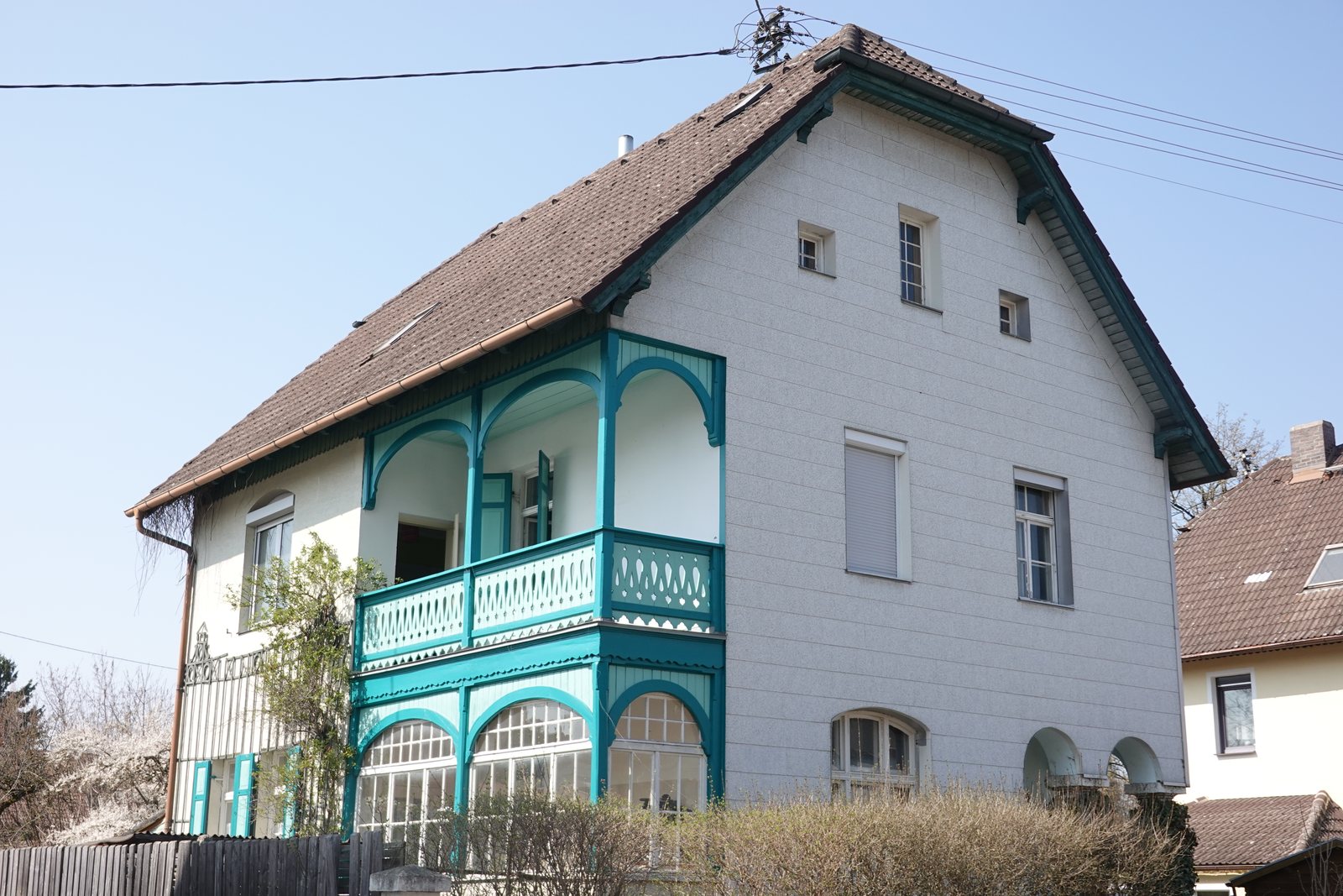 Weißes Wohnhaus mit türkisem Holzbalkon in Fürstenfeldbruck