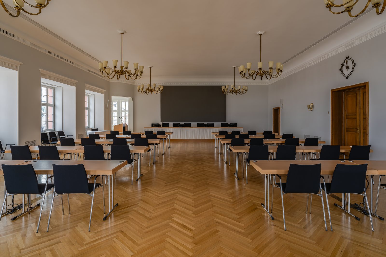 Sitzungssaal mit Tischreihen und Stühlen vor dem Vorstandstisch